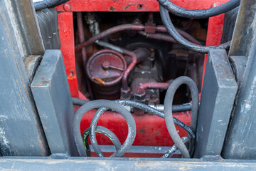 Tangled Rusty Hoses and Hydraulic Components in Exposed Red Tractor Engine Compartment