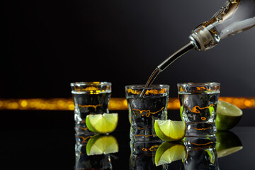 Strong alcoholic drink and lime slices on a black background.