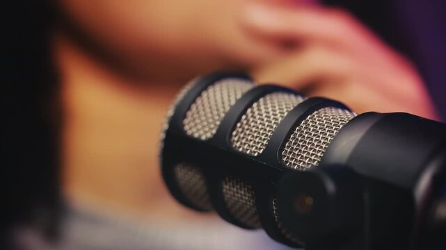Close-up of radio studio microphone as female creator records podcast
