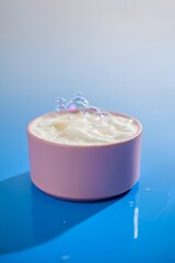 Moisturizing cream in pink container with soap bubbles