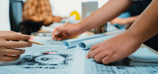 A dynamic workspace showcasing designers engaged in collaborative planning, drafting intricate technical drawings and blueprints. A creative and professional environment. SACTR