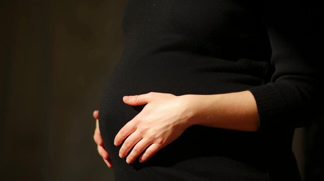 A pregnant woman on her last trimester rubs her belly, comforting herself