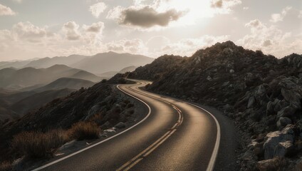 Winding road through mountain landscape under cloudy sky at sunset.