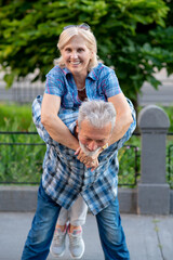Happy senior couple having fun and enjoying outdoor piggyback ride