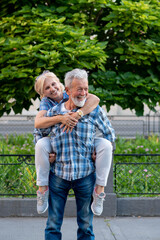 Happy senior couple having fun and enjoying outdoor piggyback ride
