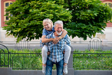 Happy senior couple having fun and enjoying outdoor piggyback ride
