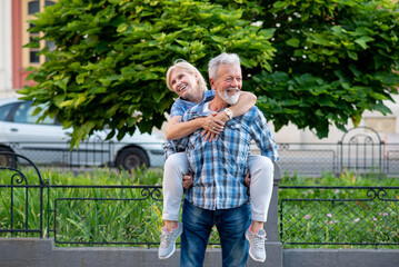 Happy senior couple having fun and enjoying outdoor piggyback ride
