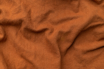 Close-up of wrinkled brown cotton fabric, top view. Waves of natural, eco-friendly fabric, abstract background of clothing material. Cotton fabric texture, textile industry, fashion
