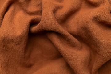 Close-up of wrinkled brown cotton fabric, top view. Waves of natural, eco-friendly fabric, abstract background of clothing material. Cotton fabric texture, textile industry, fashion