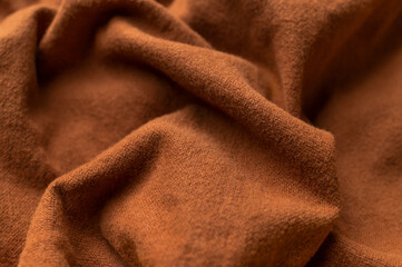 Close-up of wrinkled brown cotton fabric, top view. Waves of natural, eco-friendly fabric, abstract background of clothing material. Cotton fabric texture, textile industry, fashion