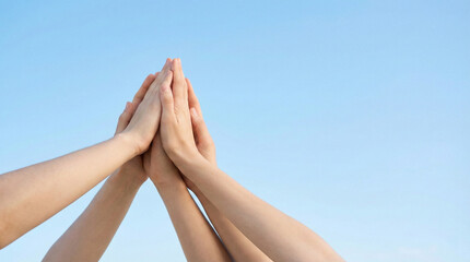diverse human hands reaching up and joined together with open sky background and clear copy space for business teamwork concepts