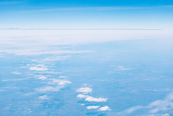 Obraz premium Aerial view showing a distinct, clear horizon line separating deep blue upper atmosphere from lower layer of scattered white cumulus clouds. Wide expanse of sky above vast cloud layer, from aircraft