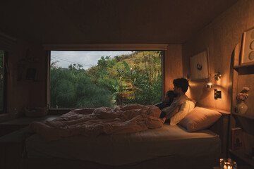 Cozy couple relaxing in bed embraced by nature's view Serene room love and peace