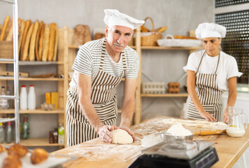 Elderly man and woman kneading and braiding dough