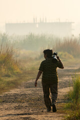 Female Wildlife Photographer Walking Through Foggy Forest with Telephoto Lens