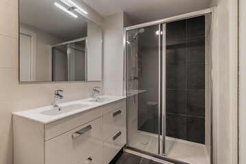 Modern bathroom with a sleek design. Features a glass shower, double sink vanity, and large mirrors. Neutral color palette with clean lines.