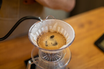 Coffee brewing process using a pour-over method. A filter is placed in a dripper, with coffee grounds and hot water creating a rich brew.