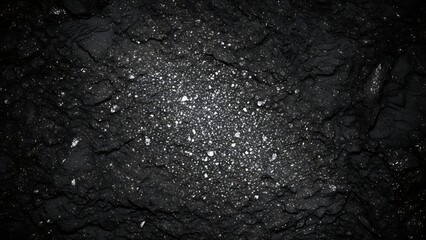Dark asphalt road surface with white specks and cracks
