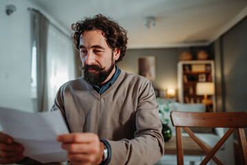 Fototapeta premium Man concentrating reading document at home feeling concerned