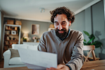 Happy man receiving good news with mail at home