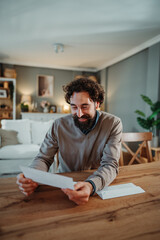 Obraz premium Man reading letter smiling receiving good news at home