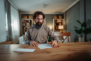 Young man reading important document at home