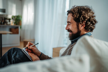 Man writing thoughts in his notebook at home