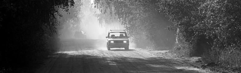 A dusty dirt road in the forest in summer, at sunset, backlit by dust and dirt, road repairs in the forest © Torkhov