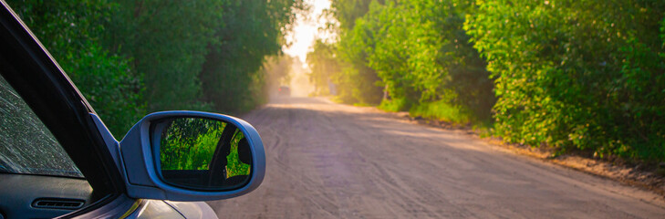 A dusty dirt road in the forest in summer, at sunset, backlit by dust and dirt, road repairs in the forest © Torkhov