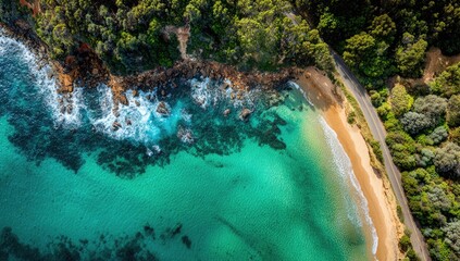 Aerial view captures a sun-kissed beach embraced by turquoise waters and a lush, verdant shoreline. A winding road borders the beach