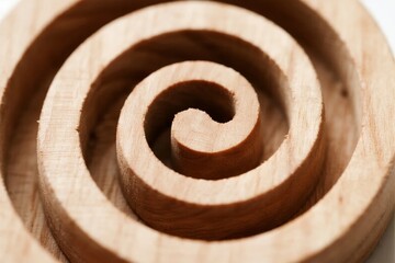 Close-up of a wooden spiral carved from natural wood, showcasing concentric circular patterns and grain texture.