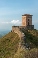 Fototapeta premium Historic tower overlooking lush hills