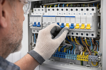 Experienced technician adjusts circuit breaker inside modern electrical panel, focusing on safe operation and proper wiring installation.