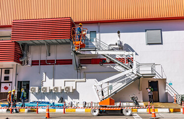 Workers are working on the Orange articulate boom lift or telescopic boom lifts and bucket crane mounted on truck for working at heights and articulating boom lift