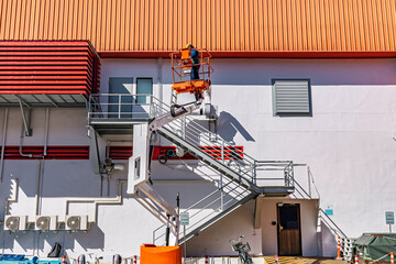 Workers are working on the Orange articulate boom lift or telescopic boom lifts and bucket crane mounted on truck for working at heights and articulating boom lift