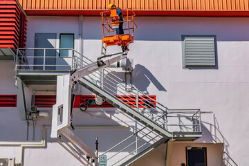 Workers are working on the Orange articulate boom lift or telescopic boom lifts and bucket crane mounted on truck for working at heights and articulating boom lift