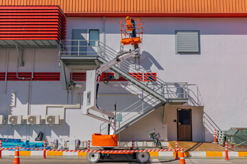 Workers are working on the Orange articulate boom lift or telescopic boom lifts and bucket crane mounted on truck for working at heights and articulating boom lift