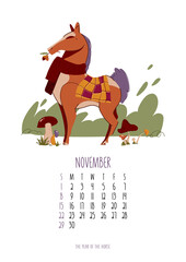 Professional November 2026 monthly calendar template featuring a cozy brown horse mascot wearing a warm red scarf and checkered blanket, gathering autumn mushrooms and an acorn in a forest meadow