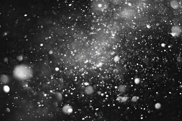 Black background with many white, glowing particles, resembling snow or dust