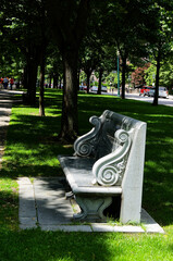 Urban Park Bench With Scrollwork: Stone Bench Along Paved Path Shaded by Trees