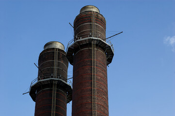 Industrial Chimneys: Tall Brick Smokestacks with Metal Platforms Standing in Outdoor Sky Vertical Shot