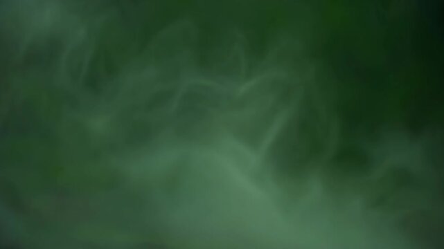 thin pale green smoke and mist swirling slowly against a dark green background in a moody atmosphere