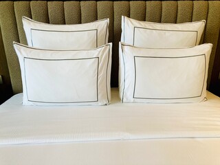 luxury hotel bed with white pillows and elegant headboard