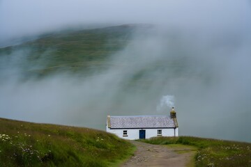 Cozy white cottage on foggy mountain road