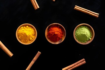 Vibrant spice powders in wooden bowls with cinnamon sticks