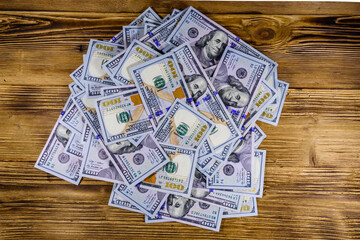 Heap of one hundred dollar banknotes on a wooden background. Top view