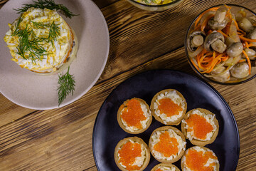 Tartlets with red caviar and festive salads on a wooden table. Festive food