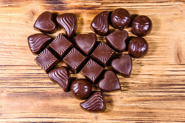Heap of chocolate candies in shape of heart on a wooden table. Valentine day concept