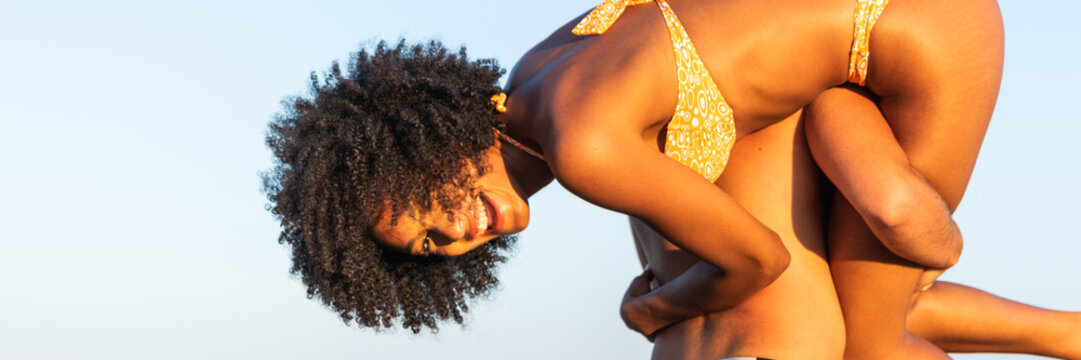 Multiracial happy Boyfriend piggybacking girlfriend on beach in summer &ndash; multi ethnic couple piggyback and love outdoor - horizontal web banner size for header
