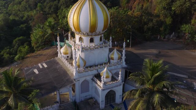 Descending circular drone shot around coastal domed mausoleum architecture